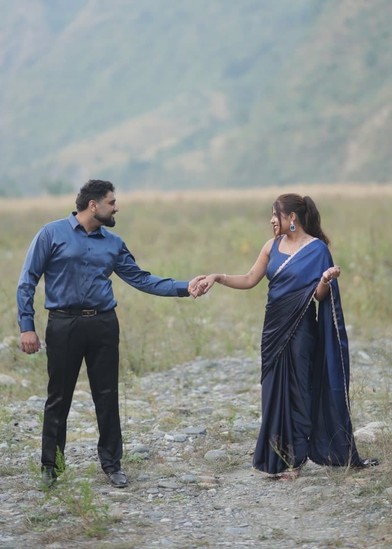 Samriti and Sarthak holding hands in a mountain valley